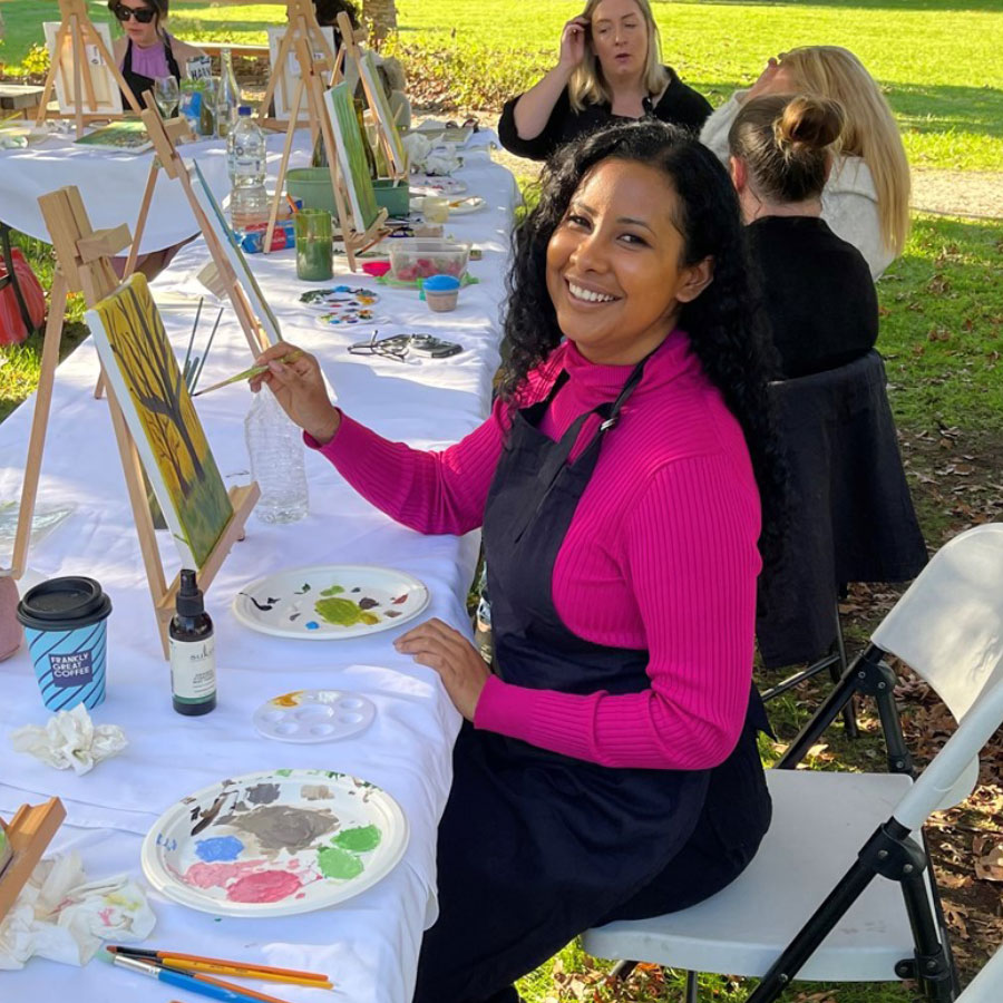 Woman painting outdoors at a Paint 'n' Sip event